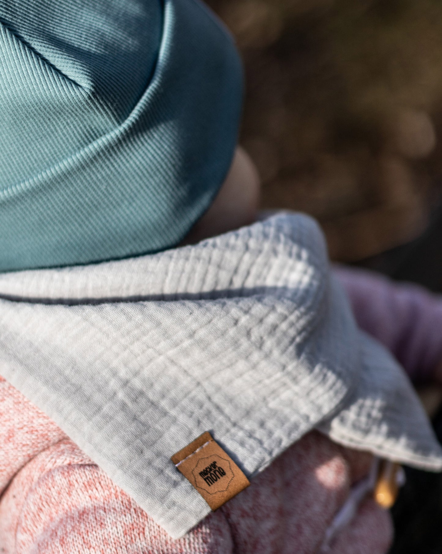 Baby mit Halstuch und Haube in der Natur